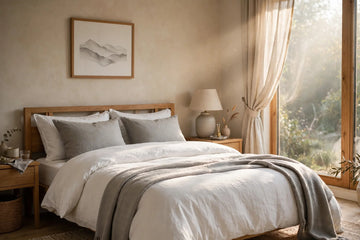 Neatly made bed with white bedding in a cozy bedroom, bathed in soft morning light.